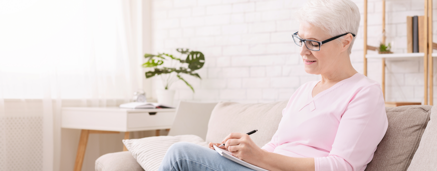 Life Assure Senior Woman Writing A List Seated At Home Hero